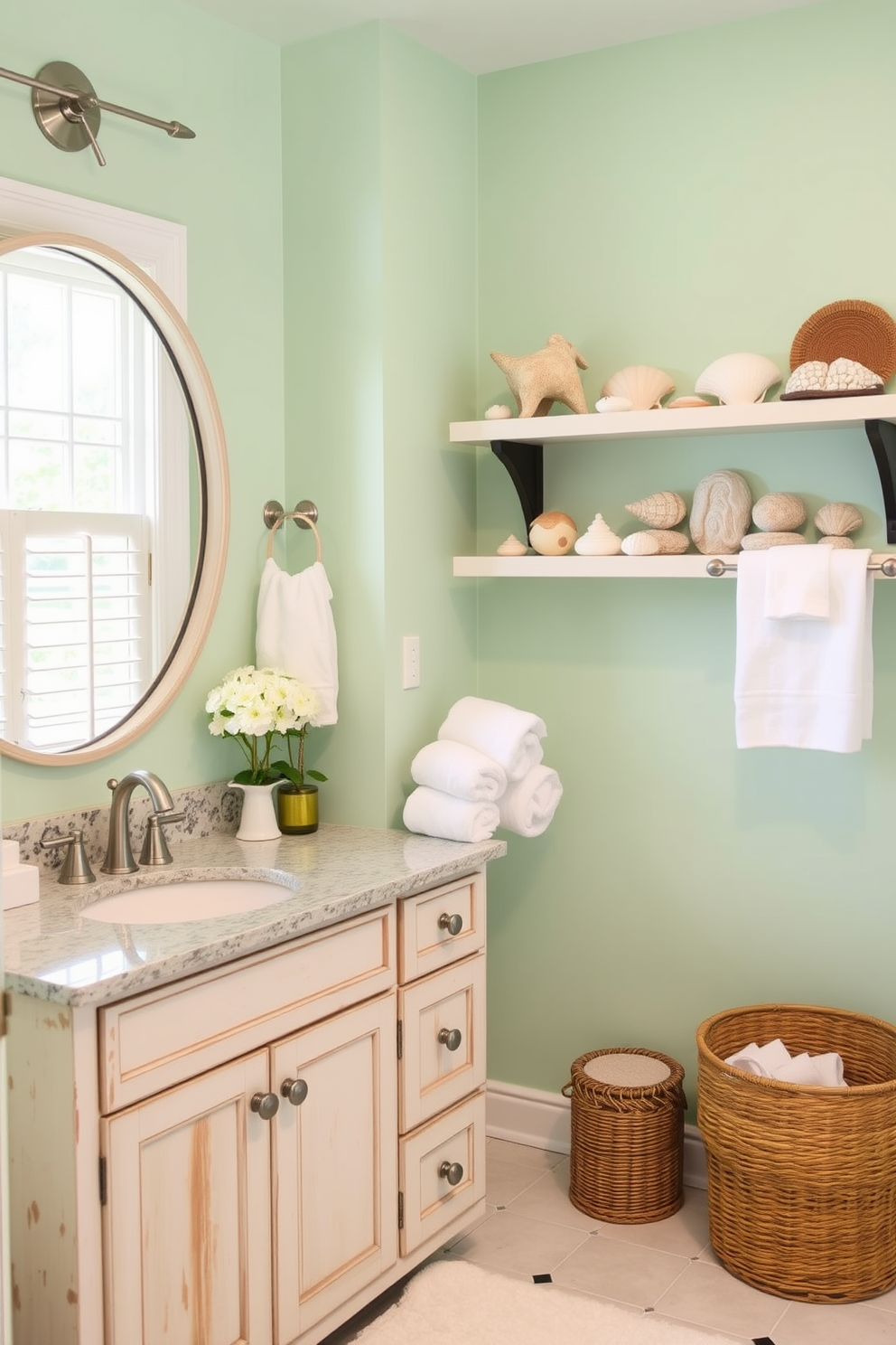 A bright summer bathroom infused with nautical accents. The walls are painted a soft seafoam green, and decorative elements include a ship wheel and a collection of seashells displayed on floating shelves. The vanity features a whitewashed wood finish with a granite countertop, complemented by brushed nickel fixtures. A large round mirror reflects natural light, while fluffy white towels and a woven basket add warmth and texture to the space.