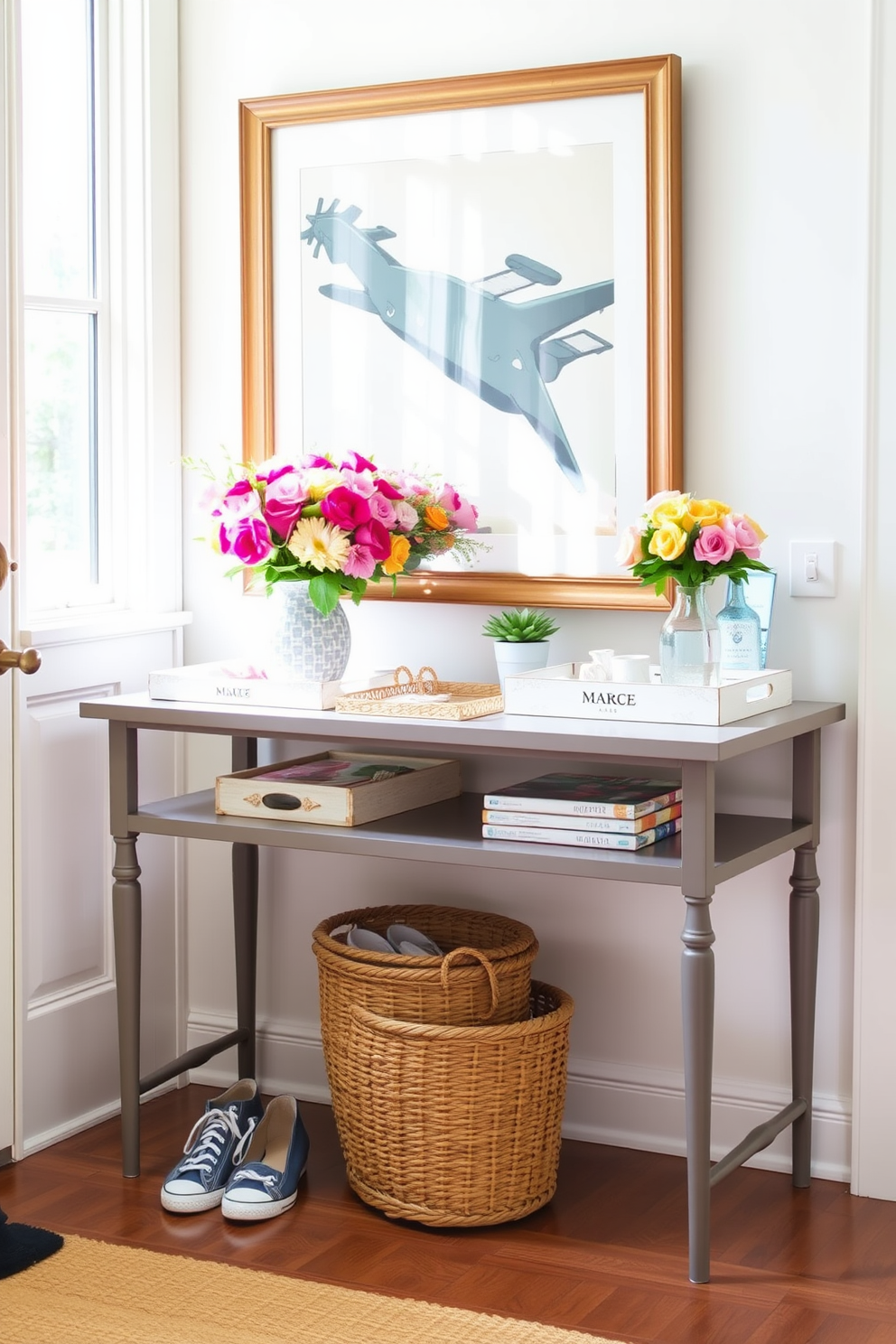 A bright and airy entryway features a stylish console table adorned with decorative trays in various sizes. The trays are filled with fresh flowers, a small potted plant, and assorted decorative items, creating an inviting and organized space. The walls are painted in a soft pastel hue, complementing the natural light streaming through the nearby window. A woven basket sits on the floor, providing additional storage for shoes and outdoor essentials, enhancing the summer vibe.