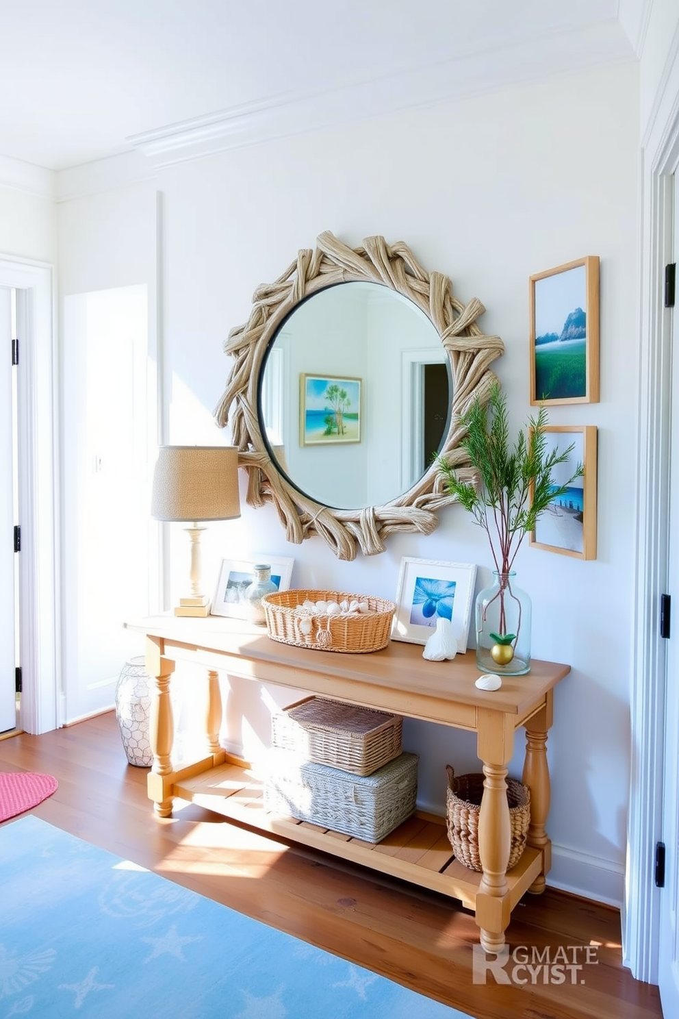 A bright and airy entryway adorned with coastal themed decor accents. The walls are painted in soft white, while a natural wood console table is topped with a woven basket and seashells. A large round mirror with a driftwood frame hangs above the table, reflecting the sunlight streaming in. A collection of beach-inspired artwork and a soft blue runner complete the inviting summer atmosphere.