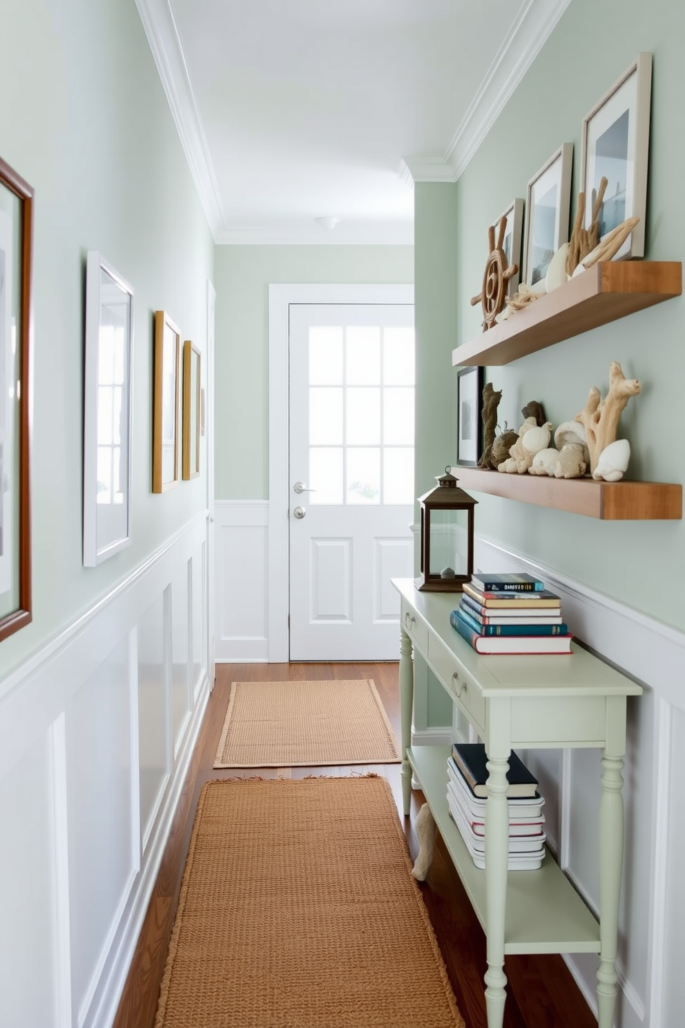 A bright and airy hallway adorned with nautical decor elements. The walls are painted in a soft seafoam green, complemented by white wainscoting and framed coastal artwork. A woven jute runner rug adds texture underfoot, while a collection of seashells and driftwood is displayed on a floating shelf. A vintage ship wheel hangs above a console table, which holds a small lantern and a stack of nautical-themed books.