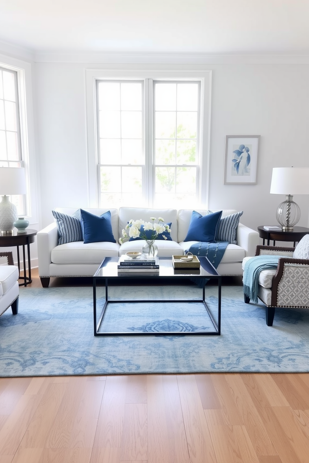 A cool blue and white color palette creates a refreshing summer living room. The space features a plush white sofa adorned with blue throw pillows and a light blue area rug that ties the room together. Large windows allow natural light to flood in, enhancing the airy feel of the room. A sleek coffee table sits in the center, complemented by decorative books and a small vase of fresh white flowers.